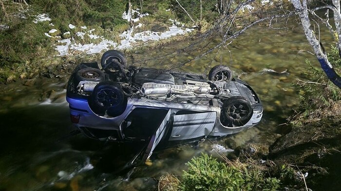 Ein Auto kam am Dach im Bach zu liegen.