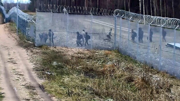 Die beiden Männer in Tarnkleidung laufen nach getaner Arbeit zurück und rufen eine Gruppe von ...