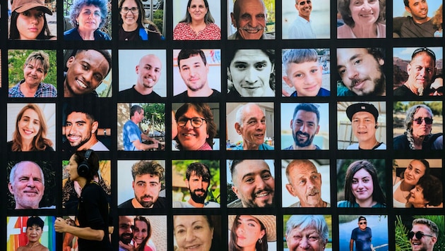 Eine Frau joggt in Jerusalem an einer riesigen Tafel mit Porträts israelischer Geiseln vorbei, die seit dem Angriff der Hamas-Kämpfer am 7. Oktober in Gaza festgehalten werden. (Bild: APA/AFP/John MACDOUGALL)