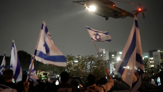 Die Menschen schwenken israelische Flaggen, als am Sonntag ein Hubschrauber mit von der Hamas aus Gaza freigelassenen Geiseln in Israel eintrifft. (Bild: ASSOCIATED PRESS)