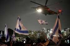 Die Menschen schwenken israelische Flaggen, als am Sonntag ein Hubschrauber mit von der Hamas aus Gaza freigelassenen Geiseln in Israel eintrifft. (Bild: ASSOCIATED PRESS)