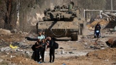 Palästinenser laufen an einem israelischen Panzer vorbei, als sie vom südlichen Stadtrand von Gaza-Stadt nach Norden fliehen. (Bild: APA/AFP/MAHMUD HAMS)