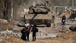 Palästinenser laufen an einem israelischen Panzer vorbei, als sie vom südlichen Stadtrand von Gaza-Stadt nach Norden fliehen. (Bild: APA/AFP/MAHMUD HAMS)