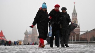 Frauen drehen bei frostigen Temperaturen eine Runde im Moskauer Stadtzentrum. Im Hintergrund sind die Basilius-Kathedrale und der Spasski-Turm zu sehen. (Bild: APA/AFP/Natalia KOLESNIKOVA)