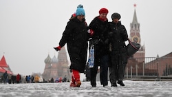 Frauen drehen bei frostigen Temperaturen eine Runde im Moskauer Stadtzentrum. Im Hintergrund sind die Basilius-Kathedrale und der Spasski-Turm zu sehen. (Bild: APA/AFP/Natalia KOLESNIKOVA)
