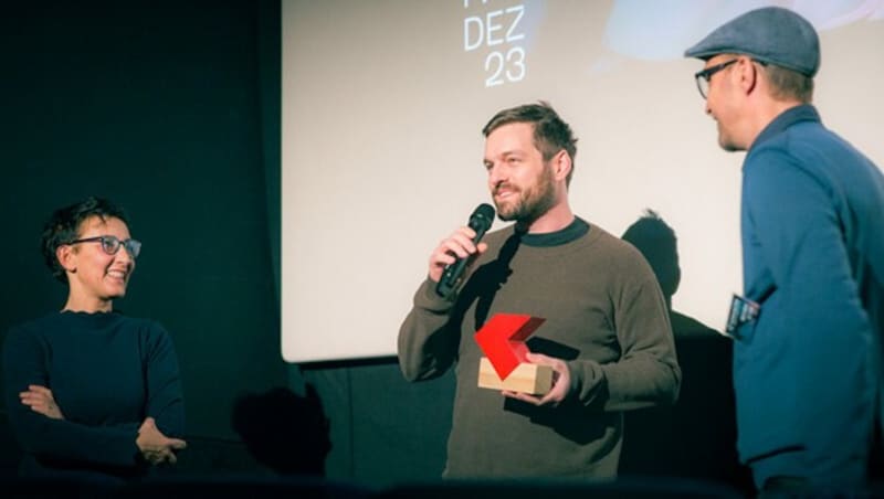 Dominik Mencej (Mitte) erhielt den K3-Langfilmpreis - hier bei der Übergabe mit den K3-Organisatoren Piera Nodari (li) und Fritz Hock (re). (Bild: K3 Filmfestival)