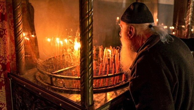 Ein Geistlicher zündet in Bethlehem vor einer Ikone eine Kerze an. (Bild: APA/AFP/HAZEM BADER)
