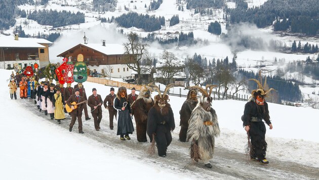 Begleitet von Musikanten ziehen die Schiach- und Schönperchten durch das verschneite Goldegg. (Bild: Gerhard Schiel)