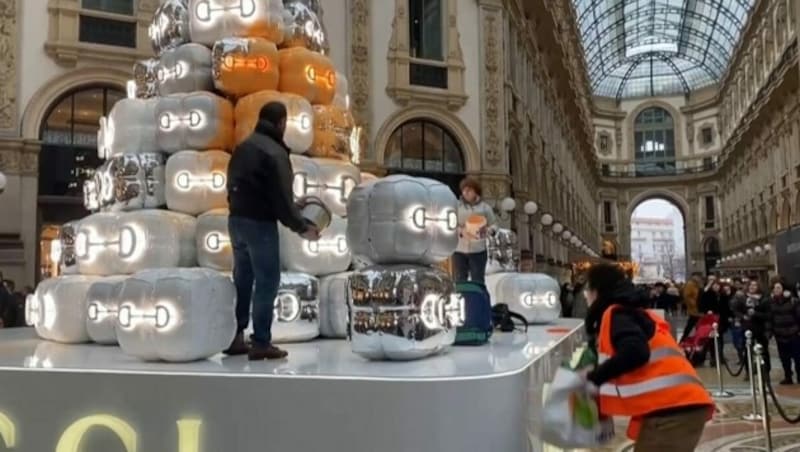 Klimaaktivisten haben im Zentrum von Mailand einen vom italienischen Modeunternehmen Gucci gesponserten, stilisierten Christbaum mit Farbe beschmiert. (Bild: kameraOne (Screenshot))