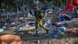 Ein israelischer Soldat patrouilliert nach dem Massaker am Ort des Geschehens. (Bild: APA/AFP/Aris MESSINIS)