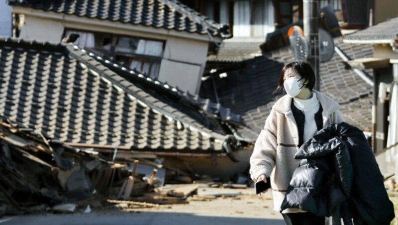 Eine Frau geht nach dem Beben in der Präfektur Ishikawa an eingestürzten Häusern vorbei. (Bild: ASSOCIATED PRESS)