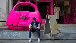 Ein Mann sitzt vor einer Modeboutique in der Küstenstadt Xiamen. Die Kaufkraft der Chinesen lässt allerdings zu wünschen übrig. (Bild: ASSOCIATED PRESS)