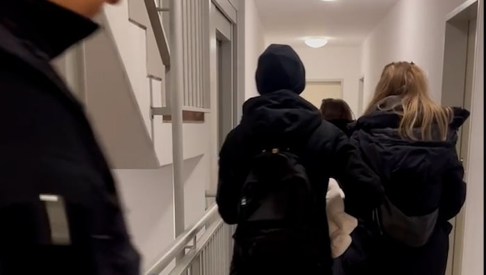 Drei Mitarbeiterinnen vom Jugendamt tragen die Babys der Anwältin aus der Wohnung.