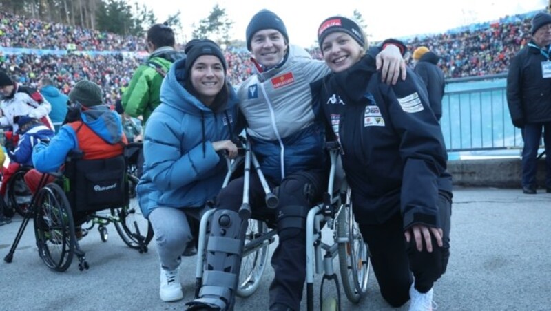 Polizei-Springer Thomas Lackner sitzt nach einem Sturz mit Beinverletzungen im Rollstuhl, dank Bobpilotin Kati Beierl (rechts) und Ringerin Martina Kuenz war er im Stadion dabei. (Bild: Birbaumer Christof)