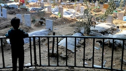 Ein palästinensischer Bub blickt auf Gräber von Menschen, die bei den Bombardements des Gazastreifens getötet worden sind. (Bild: AP)