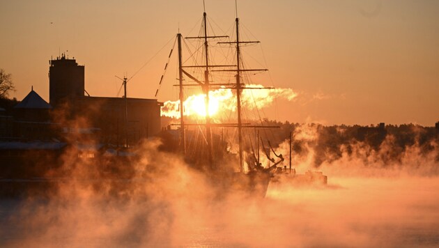 Ein historisches Trimaster-Charter-Segelschiff wird im Hafen von Oslo bei ungewöhnlichen Minustemperaturen in der Morgensonne in goldenes Licht getaucht. (Bild: AFP or licensors)