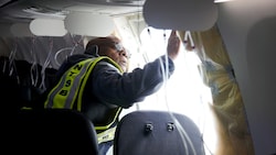 Ein Experte untersucht eine zwei Monate alte Boeing 737 Max, bei der Anfang Jänner nach dem Start in mehreren Kilometern Höhe ein Stück der Kabinenwand wegflog. (Bild: 2024 NTSB)