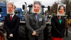 Ein mit Attrappen geschmückter Traktor mit Bildern von Bundeskanzler Olaf Scholz, Wirtschaftsminister Robert Habeck und Außenministerin Annalena Baerbock während der Bauern-Demo in Berlin am Montag. (Bild: AFP)