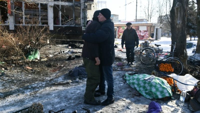 Zwei Männer umarmen sich nach dem Angriff auf den Markt. (Bild: APA/AFP/STRINGER)