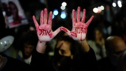 Angehörige und Unterstützer der israelischen Geiseln, die im Gazastreifen von der Hamas festgehalten werden, demonstrieren in Jerusalem. Auf den Händen mit falschem Blut steht in hebräischer Schrift: „Die Zeit läuft ab“. (Bild: AP)