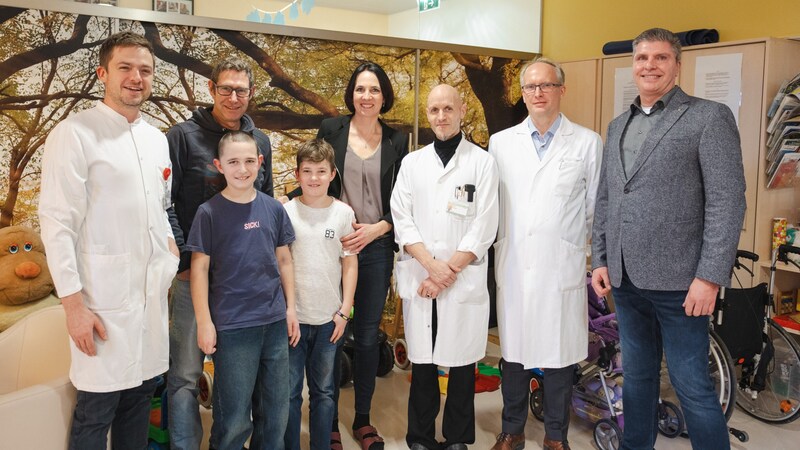 V. l.: Neurochirurg Johannes Pöppe, Felix (10), Papa Andreas H., Bruder Simon (8), Mama Monika H., Kinder-Neurochirurg Matthias Krause, Vorstand Roman Metzger und Werner Wurm, Leiter des 3D-Drucklabors (Bild: SALK/Leon Bernhofer)