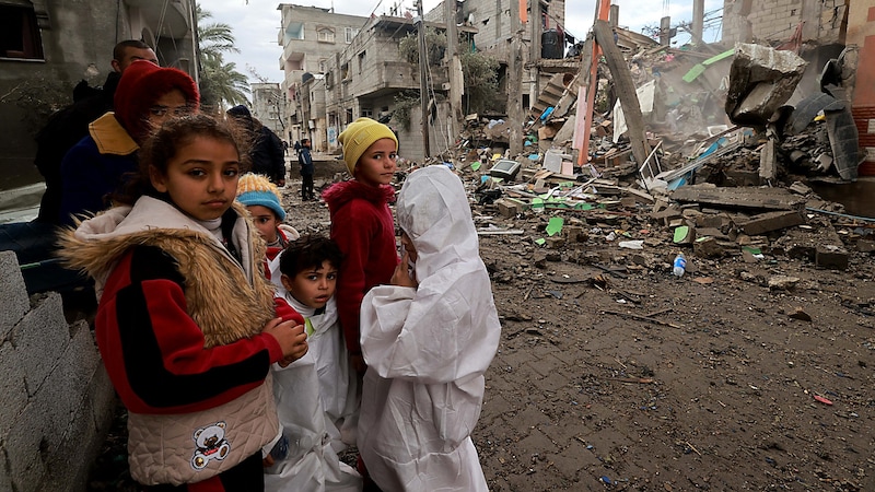 Děti před zničenou budovou v jižní části pásma Gazy. (Bild: APA/AFP)