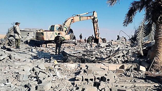Takarítási munkálatok a síita milíciák infrastruktúrája elleni légicsapást követően az iraki al-Ka'im városában. (Bild: AP)