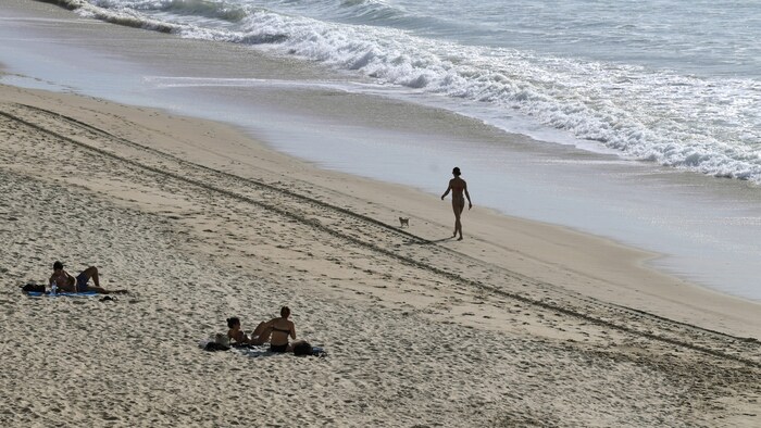 Sun-seekers enjoy the unusually warm weather at Santa Maria Beach in Cadiz on January 26, 2024