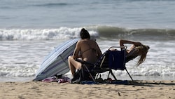 Zwei Frauen tanken Ende Jänner 2024 an einem Strand in Cadiz, Spanien bei Temperaturen um die 30 Grad Sonne. (Bild: AFP )
