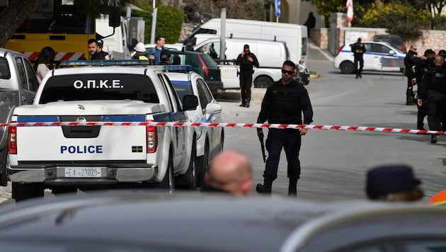 Polis güçleri katliamın ardından Atina yakınlarındaki nakliye şirketinin önündeki alanı güvenlik altına aldı. (Bild: Associated Press)