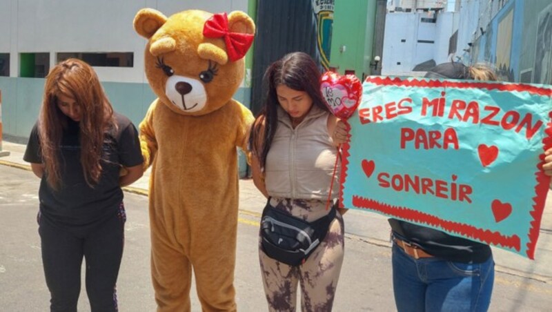 Ein als kuscheliger Riesen-Teddybär verkleideter Fahnder mit den beiden festgenommenen Frauen (Bild: APA/AFP/Carlos Mandujano)