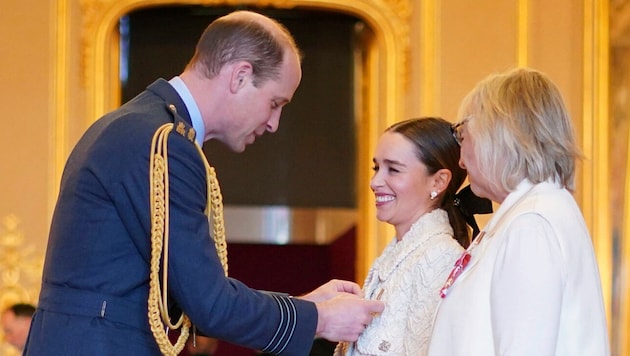 Prinz William verleiht Emilia Clarke und ihrer Mutter für ihre Verdienste im britischen Gesundheitswesen den „MBE“-Orden. (Bild: APA/Yui Mok/PA via AP)