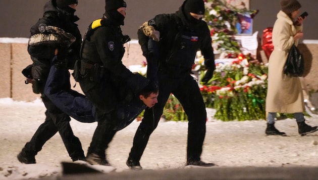 Rendőrök őrizetbe vesznek egy férfit, aki virágot helyezett el Navalnijnak Szentpéterváron. (Bild: AP)