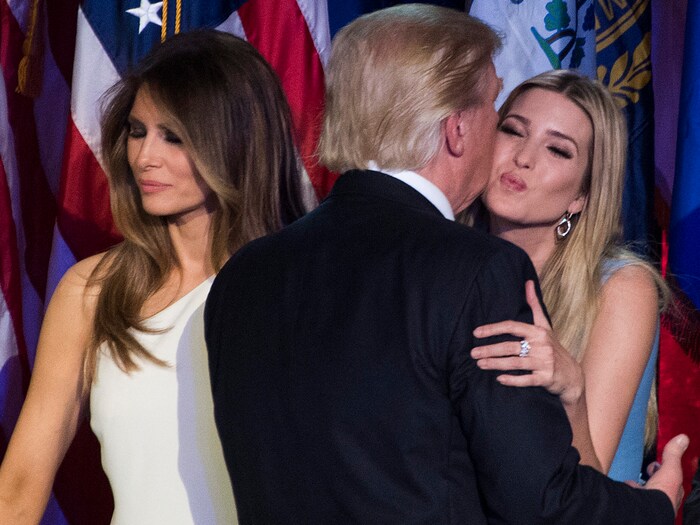 Donald Trump, eşi Melania uzaklara bakarken kızı Ivanka'yı yanağından öpüyor.