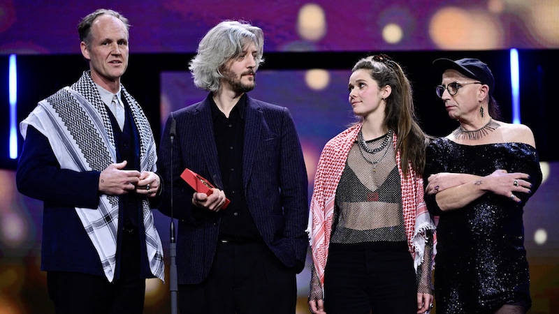 Ben Russell (links) und Guillaume Cailleau (2. v. links) bei der BerlinaleBen Russell (links) mit Palästinenserschal und Guillaume Cailleau hetzen auf der Berlinale-Bühne gegen Israel. Zuvor hatten die beiden den Preis für den besten Film für „Direct Action“ erhalten. (Bild: APA/AFP/John MACDOUGALL)