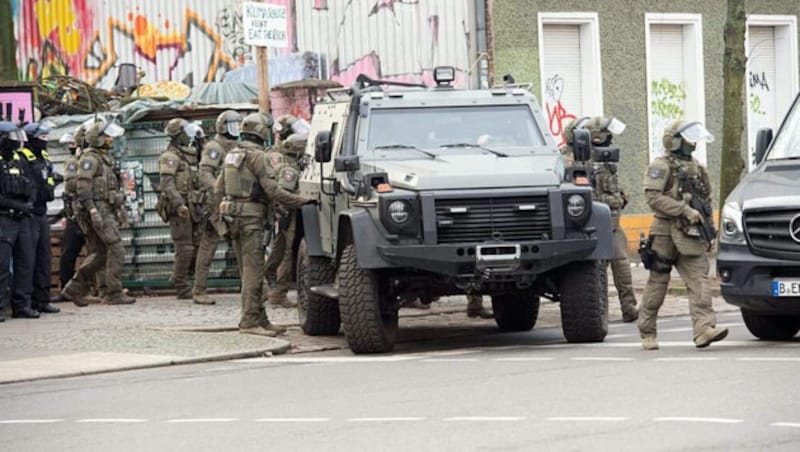 Polizisten stehen am Sonntag bei einem gepanzerten Fahrzeug. Der Einsatz steht im Zusammenhang mit der Fahndung nach den beiden noch flüchtigen mutmaßlichen RAF-Räubern. (Bild: APA/dpa/Paul Zinken)