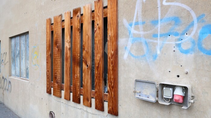 A broken window with a wooden grille at the old building yard.
