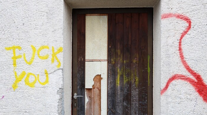 Graffiti with insulting words can be found on the old building yard.
