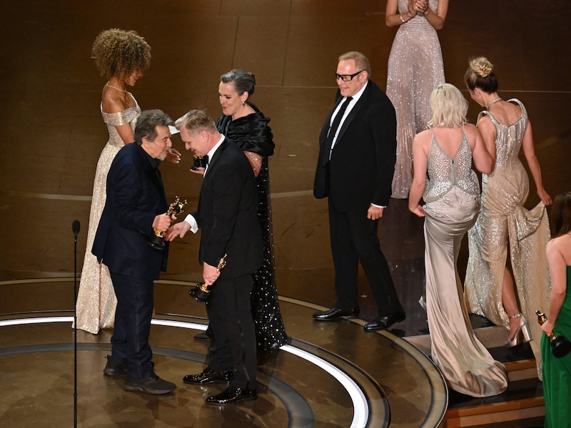 Die britische Filmproduzentin Emma Thomas, der US-Filmproduzent Charles Roven und der britische Filmemacher Christopher Nolan nehmen den Preis für den besten Film von dem US-Schauspieler Al Pacino entgegen. (Bild: APA/AFP/Patrick T. Fallon)