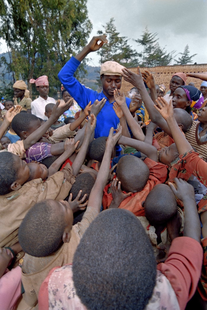 Ein Mann in Ruanda verteilt Essen an hungrige Kinder.