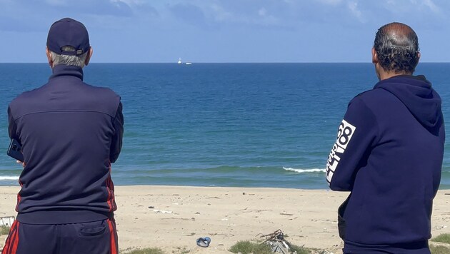 Hombres palestinos observan cómo el barco "Open Arms", que zarpó de Larnaca (Chipre) con ayuda humanitaria, se acerca a la costa de la ciudad de Gaza. (Bild: AFP)