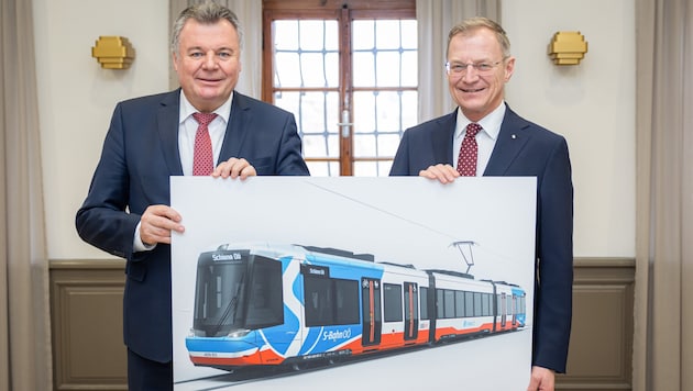 The ground-breaking ceremony for the construction of a regional light rail system is scheduled for 2027 at the earliest. Provincial Councillor Steinkellner (left) and Governor Stelzer show what the railroad trains will look like. (Bild: ÖVP/Antonio Bayer)