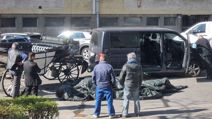 Le cheval mort gisait au milieu de la rue sous la bâche. 