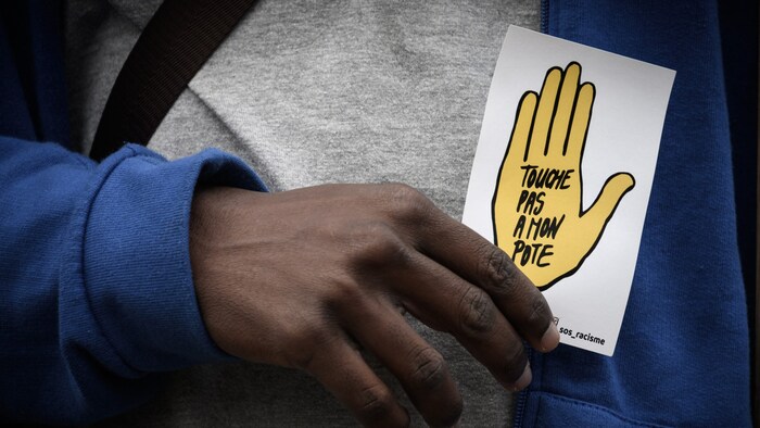 Ein Demonstrant hält eine Karte mit dem Slogan „touche pas à mon pote” (Fass meinen Freund ...