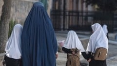 Eine Frau bringt ihre jüngsten Töchter in die Schule. (Bild: AFP)