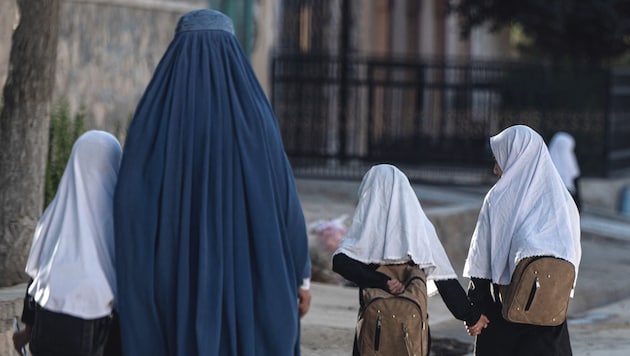 Une femme amène ses plus jeunes filles à l'école. (Bild: AFP)