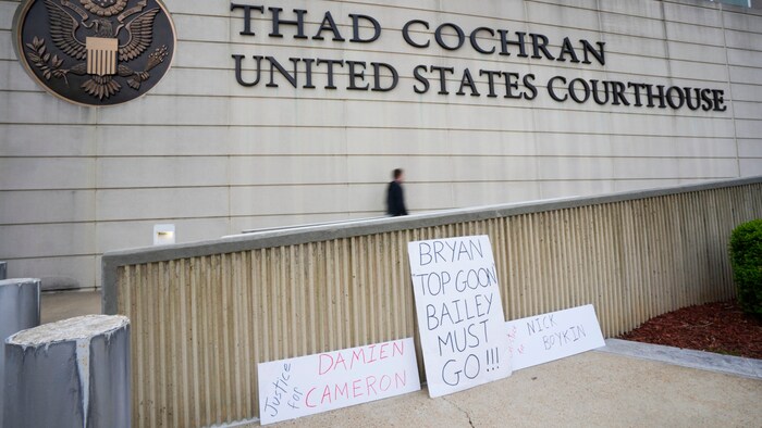 Protest signs line the sidewalk outside the Thad Cochran United States Courthouse in Jackson
