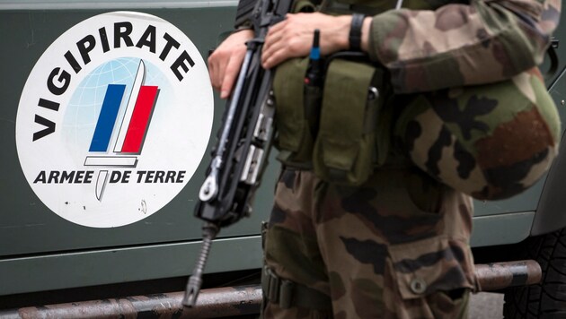 Fransa'da teröre karşı alınan güvenlik önlemlerini ifade eden "Vigiprate" logosunun yanında bir asker (arşiv görüntüsü) (Bild: APA/AFP/POOL/IAN LANGSDON)