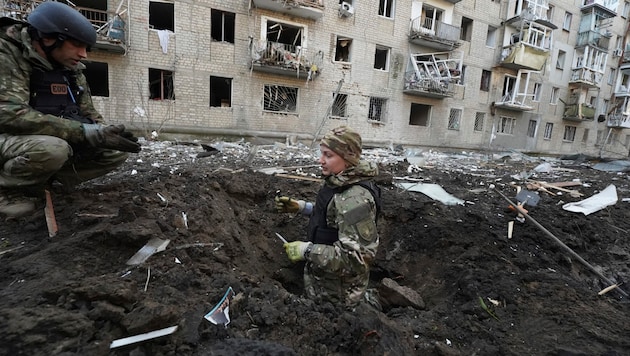 Ukrayna polis personeli bir çarpma kraterini inceliyor. (Bild: AP)