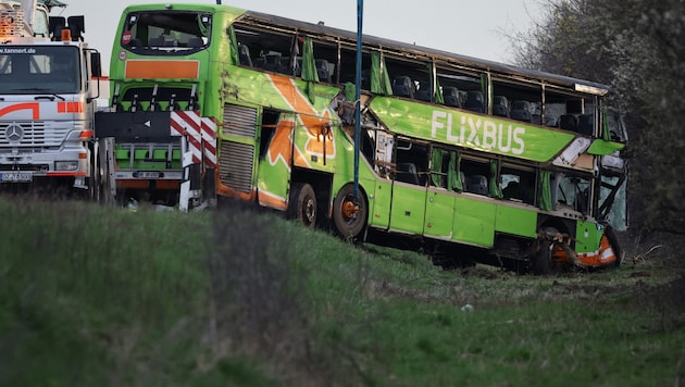 Több órába telt, mire a felborult autóbuszt övekkel helyre tudták állítani. (Bild: APA/AFP/Jens Schlueter)